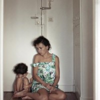 Femme et son enfant assis devant une porte close